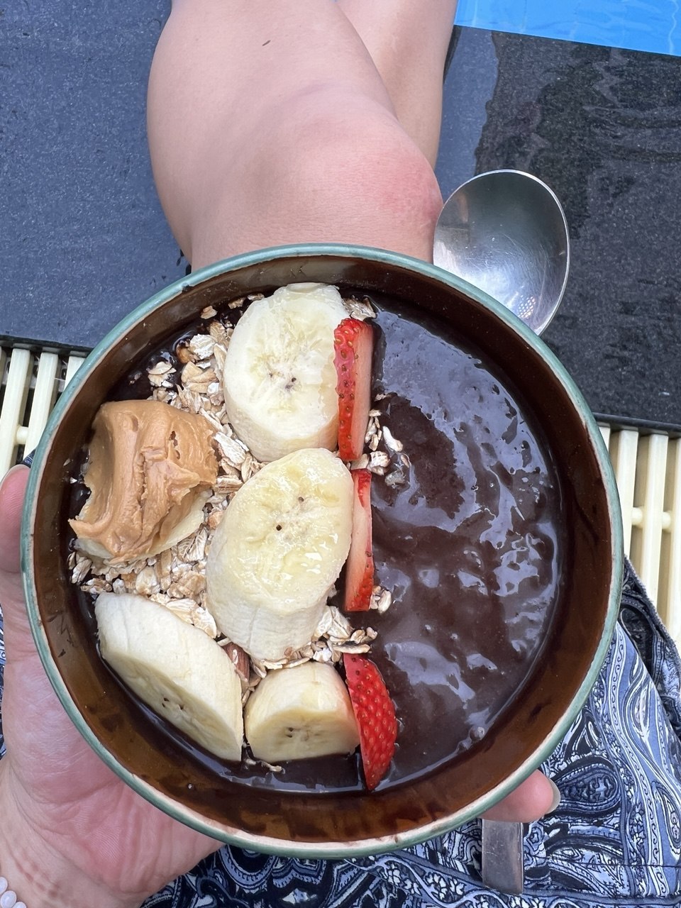 smoothie bowl with dark blended base, banana slices, strawberry slices, oats or granola, and a scoop of peanut butter