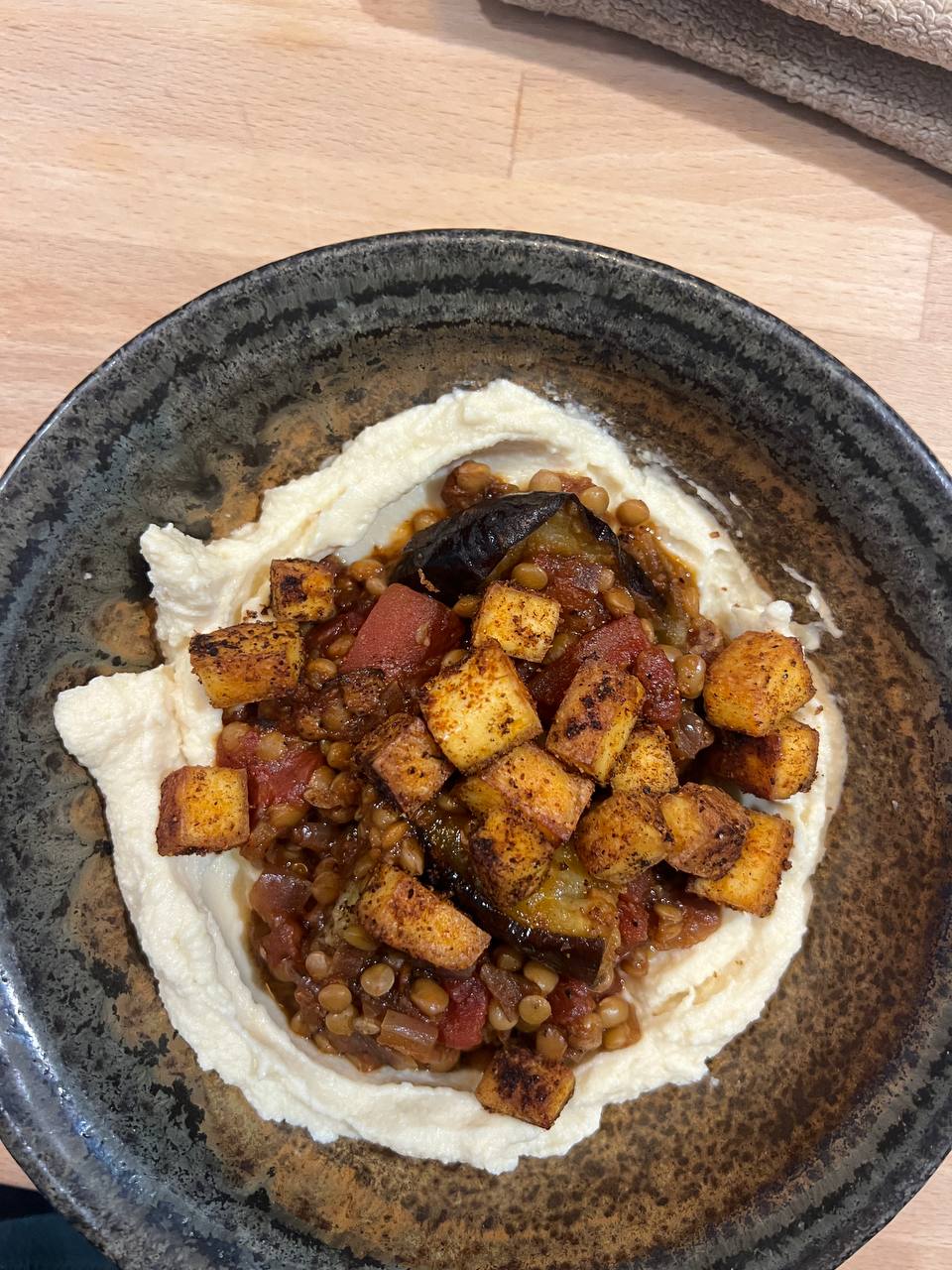 bowl with hummus base, lentil-tomato-eggplant mixture, and grilled tofu cubes
