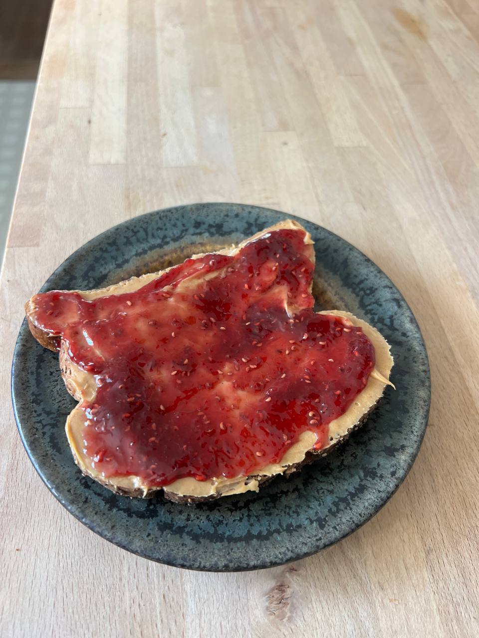 open-faced slice of bread with peanut butter and raspberry jam