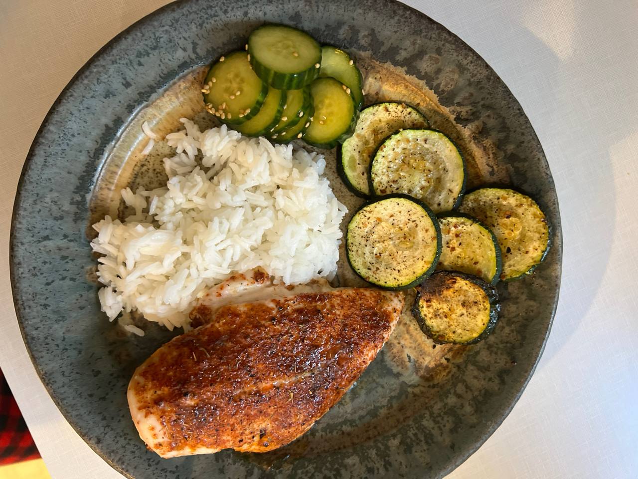 Seared/roasted chicken breast, Cooked white rice, Roasted zucchini rounds, Cucumber slices in soy sauce and rice vinegar dressing with sesame seeds